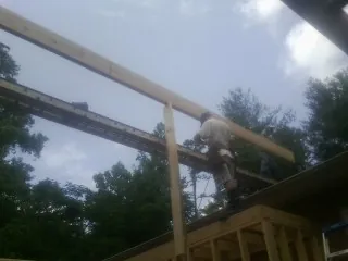 Carpenter setting a ridge beam over a new addition frame — Ice Dam Removal by Roofing Brothers in Wilsons Mills