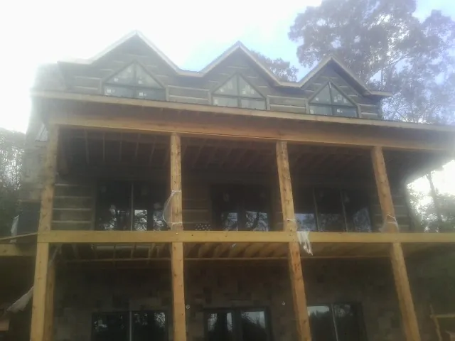 Dormers and porch framing on a large log home under construction — Roof Coating work by our crew in Wilsons Mills