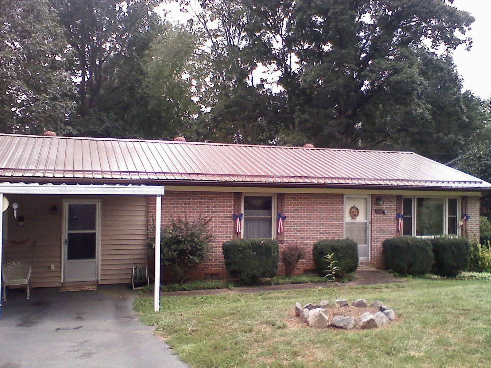 Bronze metal roof and carport on a brick ranch home — Roof Repair work by our crew in Wilsons Mills