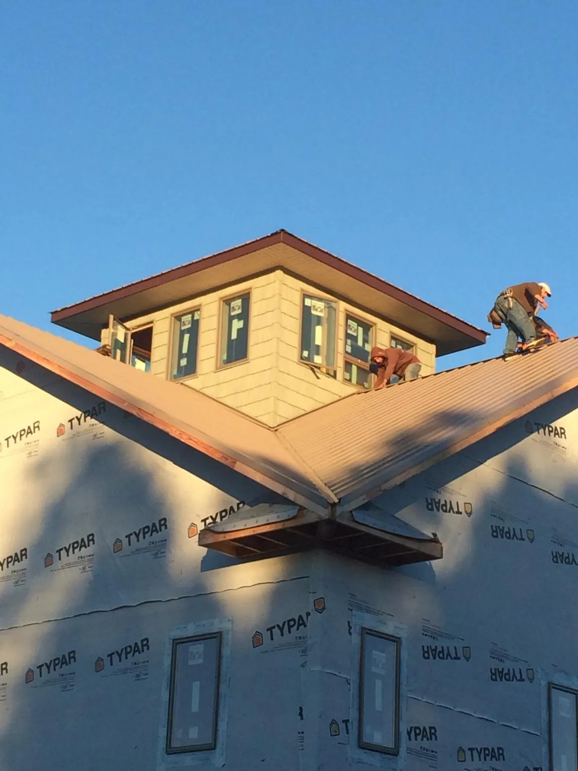Roofers working around a rooftop cupola on a new metal roof at sunset — Roof Waterproofing in Wilsons Mills by Roofing Brothers